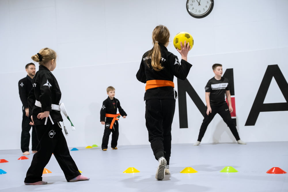 Four Ninja School students play a game at the end of the class. One is about to throw a foam ball to another.